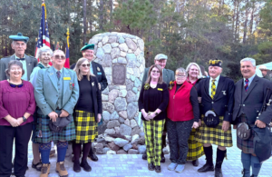 Group in kilts and tartan by memorial stone
