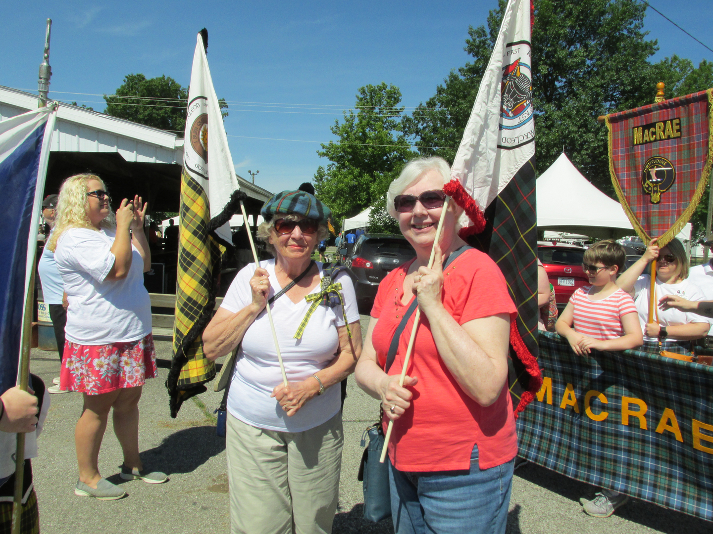 Two women holding flags at outdoor event.