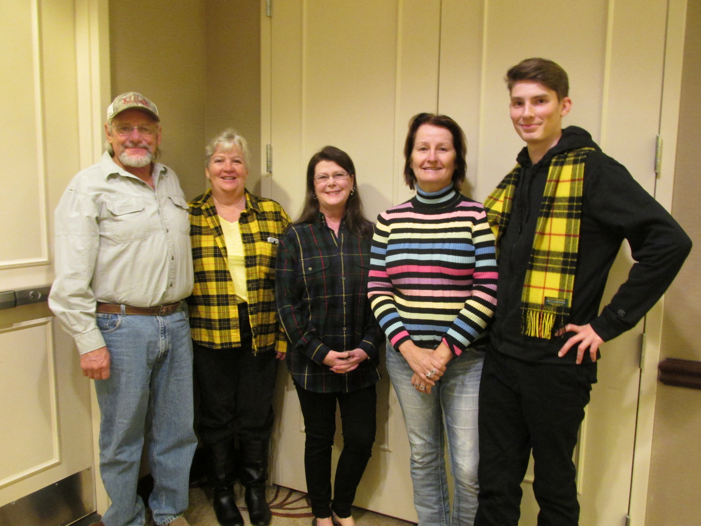 Five people standing in a row, smiling.
