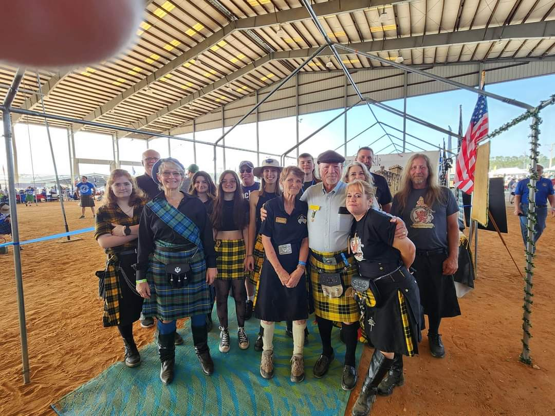 Group wearing kilts under a metal canopy.