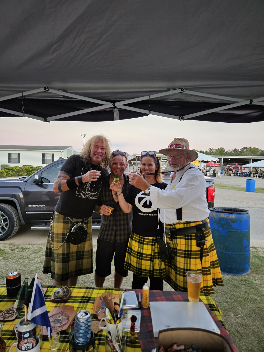 Group celebrating in kilts under a canopy.