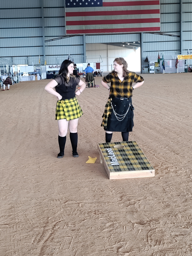 Two women in plaid skirts indoors.