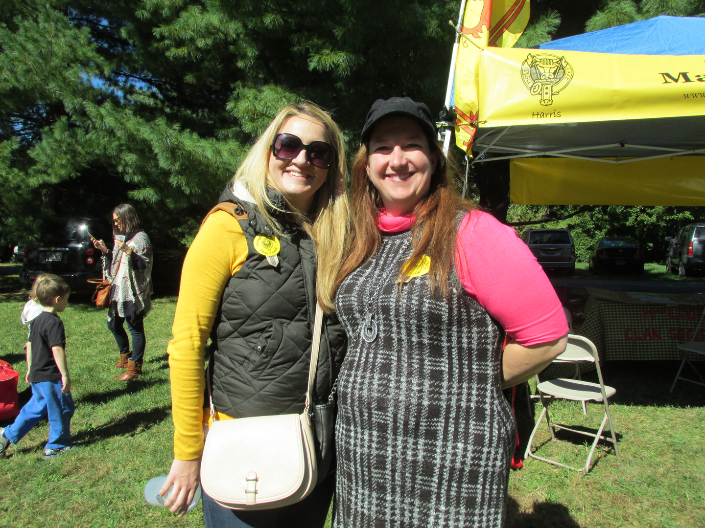 Two women smiling at outdoor event.