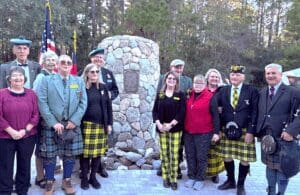 Group in kilts and tartan by memorial stone