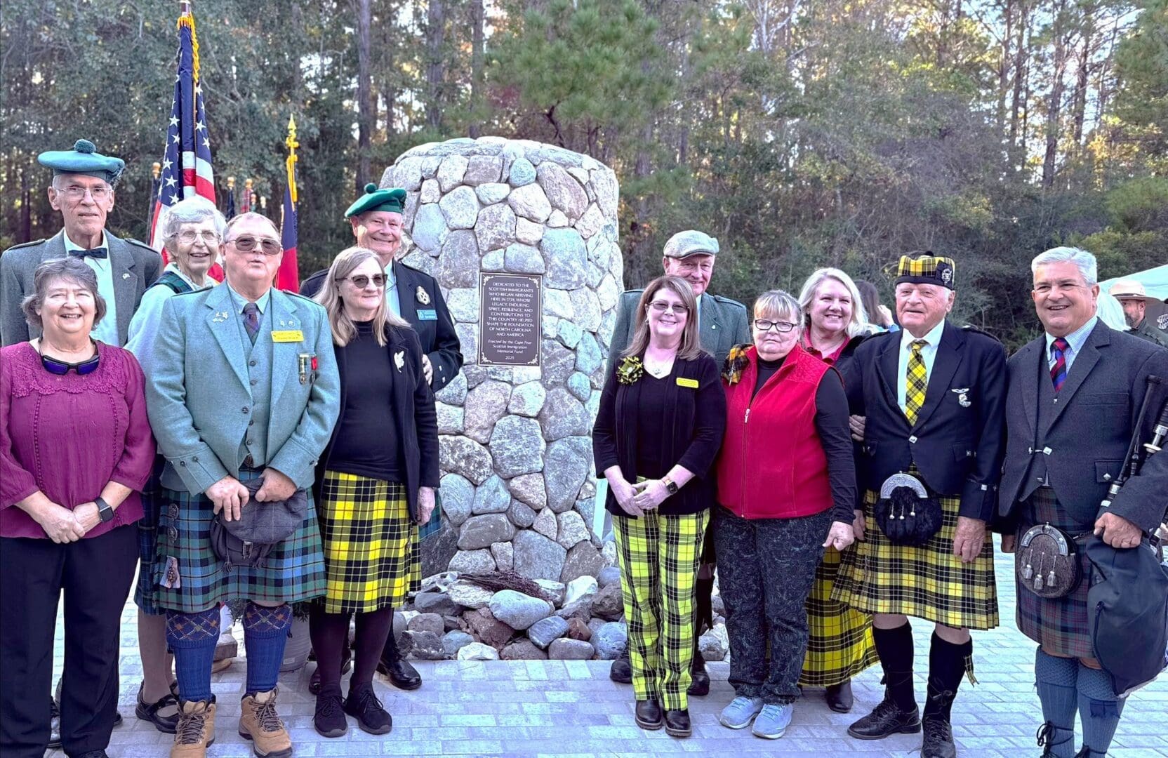 Group in kilts and tartan by memorial stone