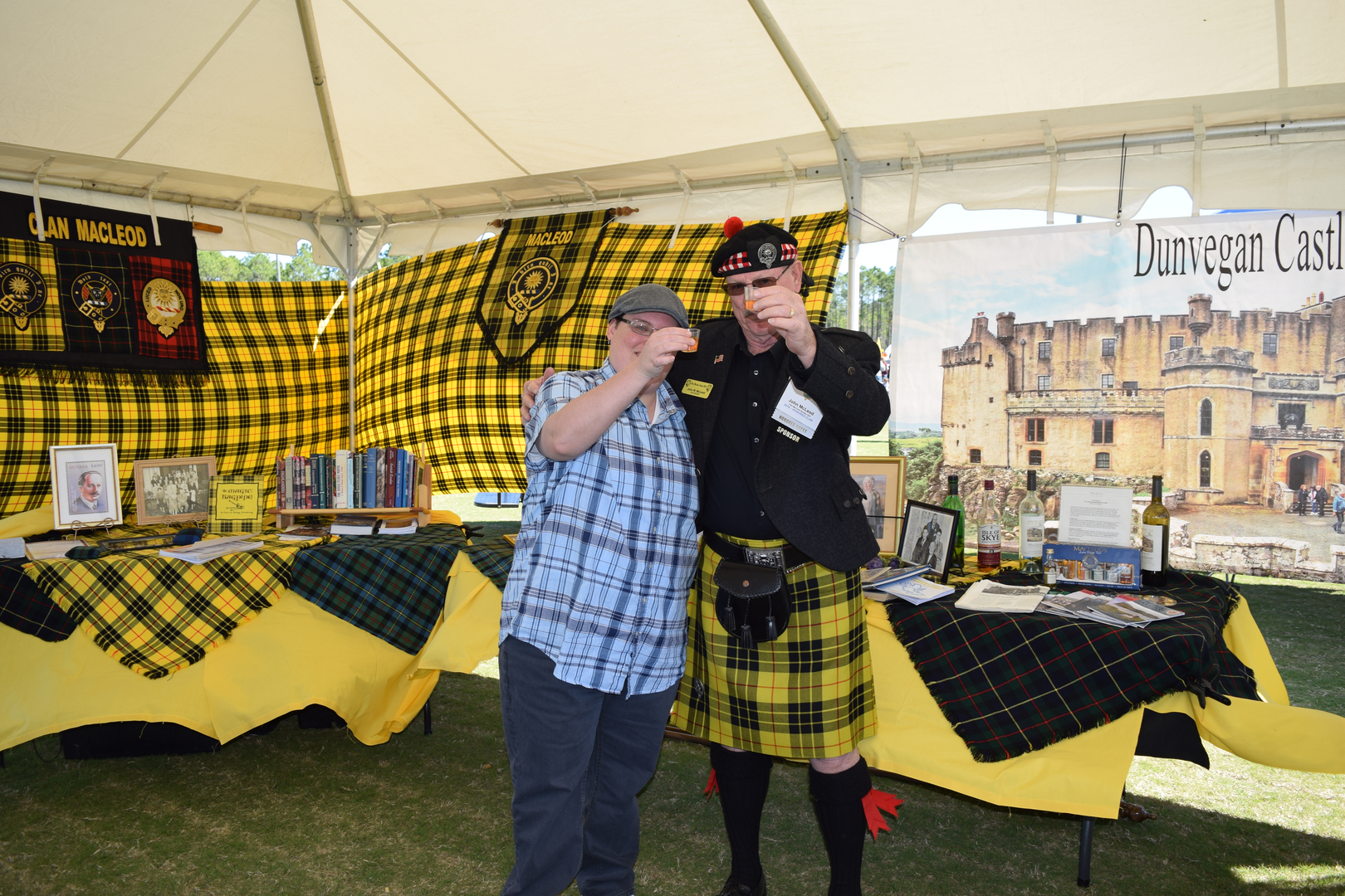 Two people toasting in a Scottish-themed tent.