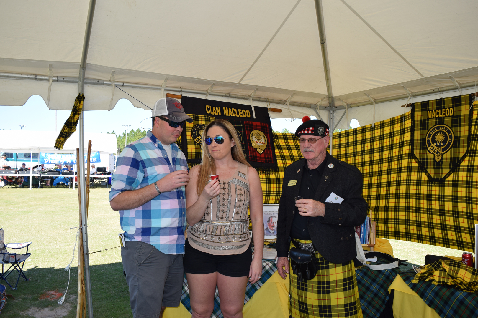 Three people under a Clan MacLeod tent.