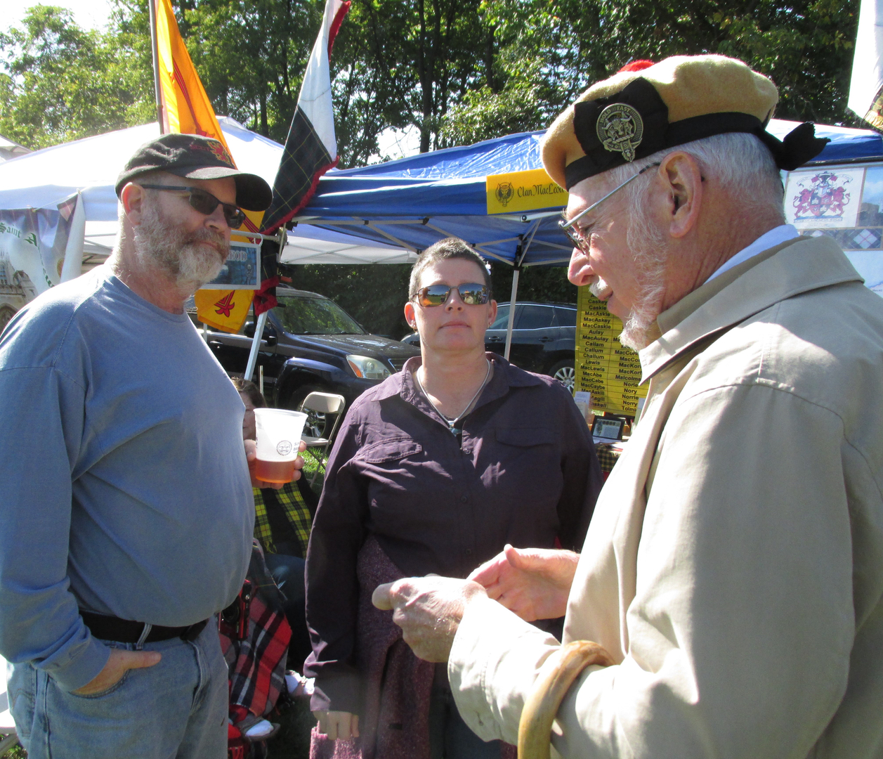Three people conversing at outdoor event.