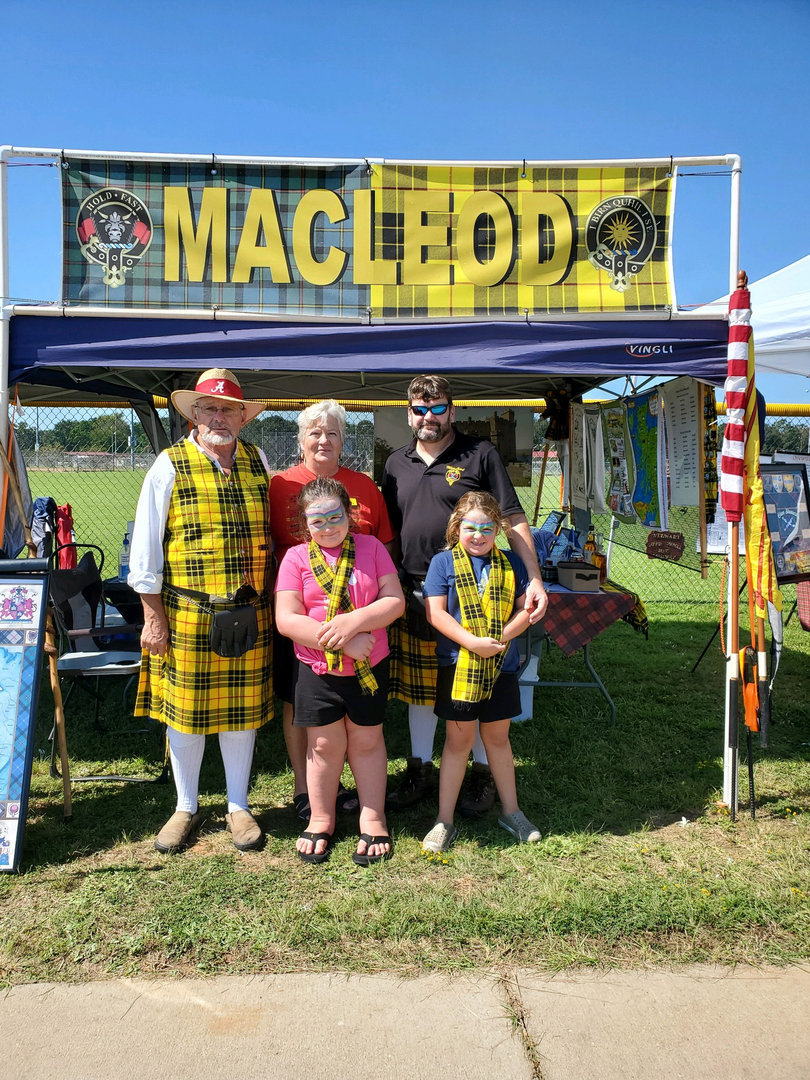 Family in front of MacLeod booth, smiling.