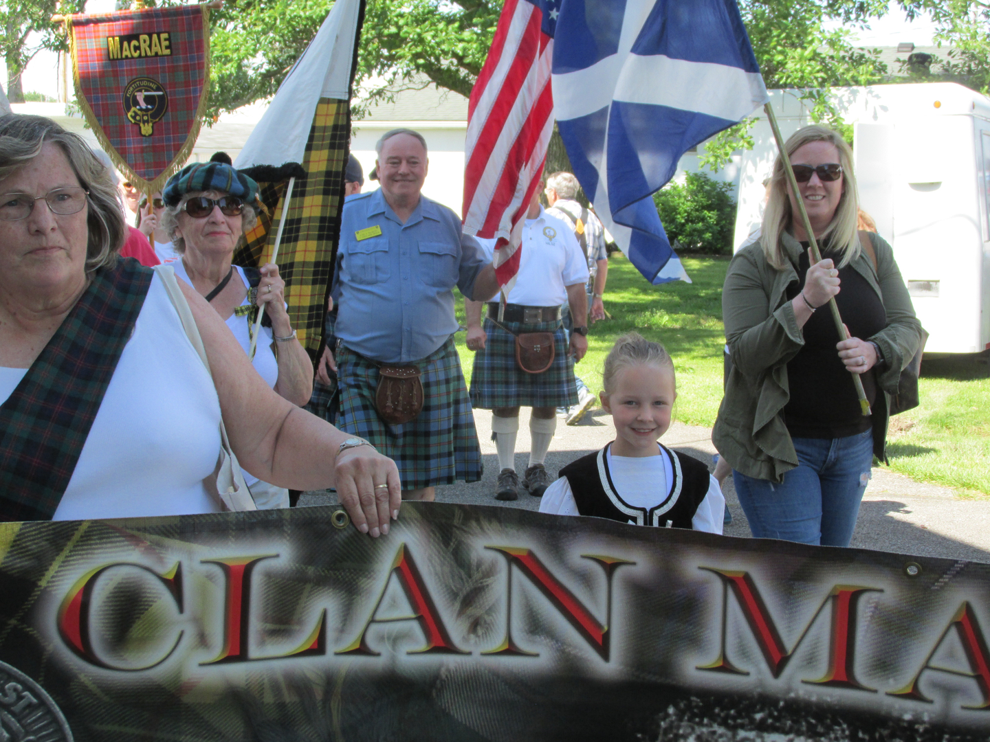 Parade participants in kilts holding flags, banner.