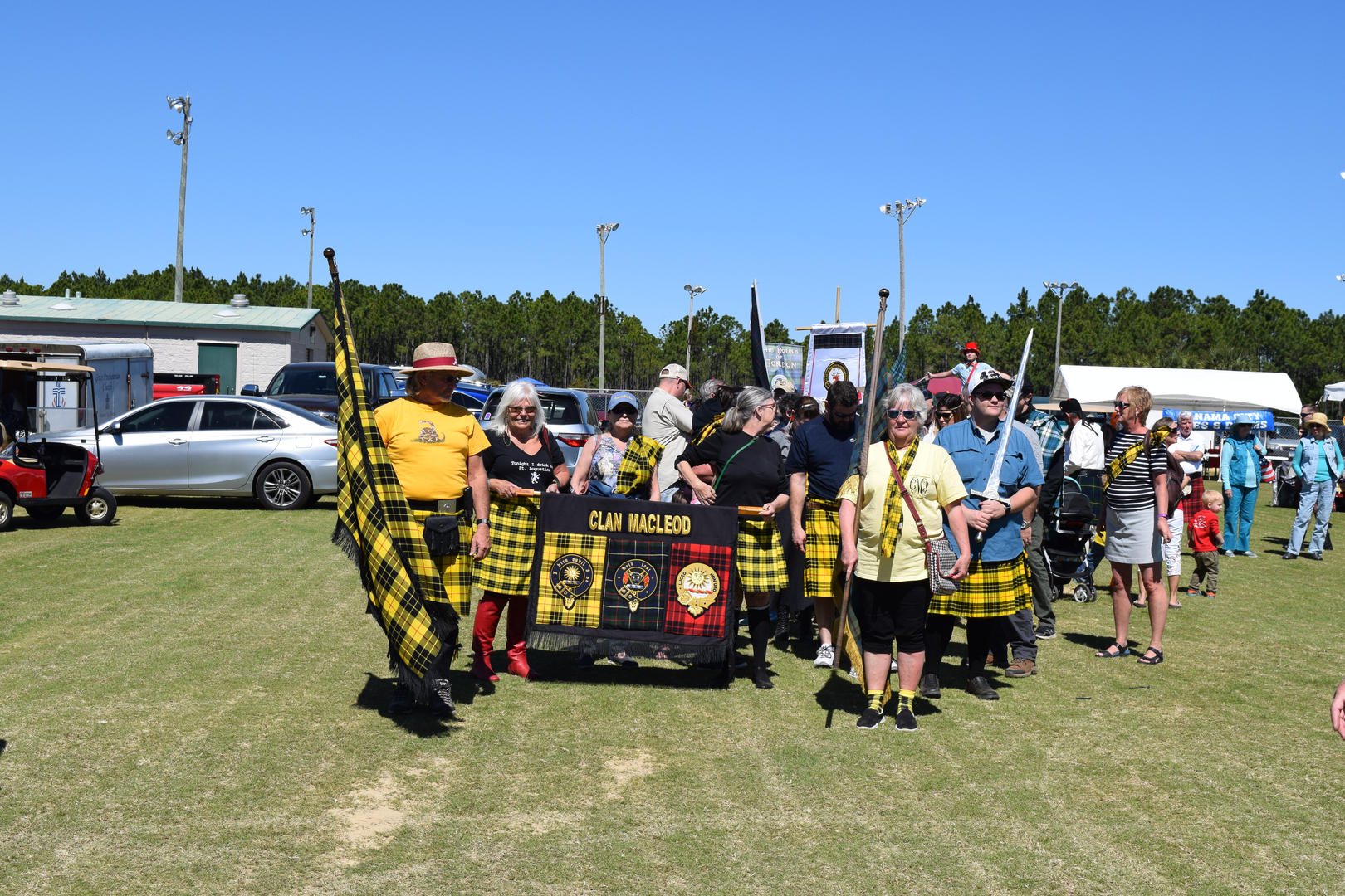 Group holding Clan MacLeod banner outdoors.