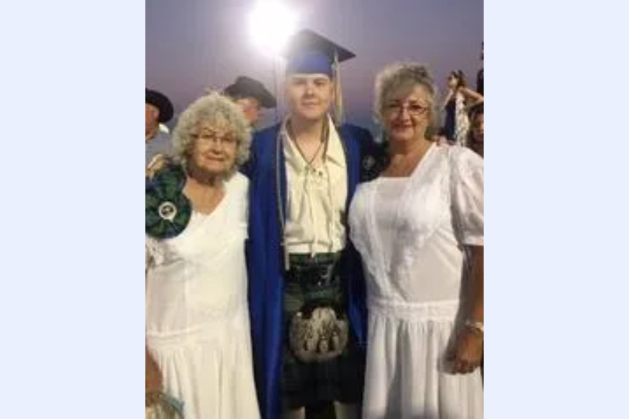 Graduate with two women in white dresses.