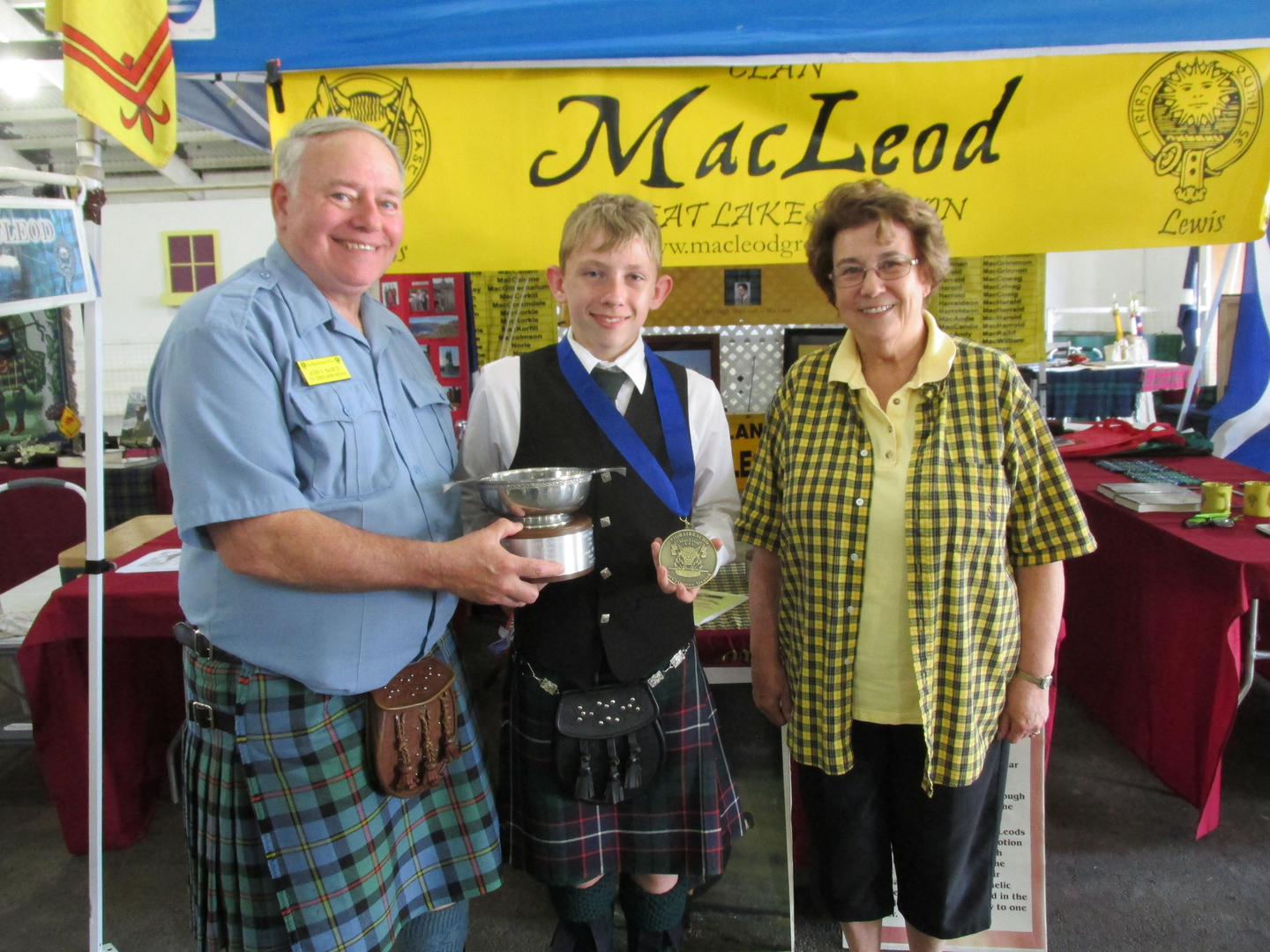 Three people in traditional Scottish attire smiling.