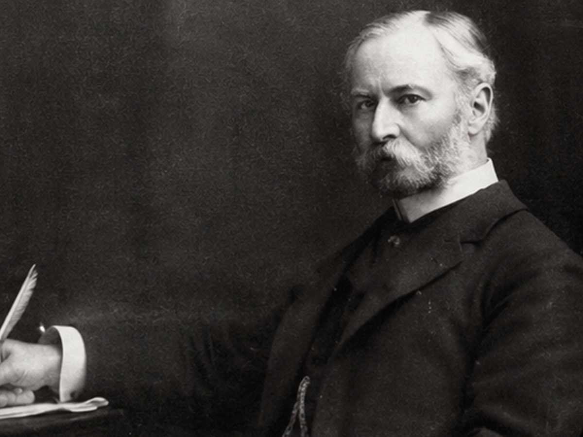 Bearded man seated with a quill pen.