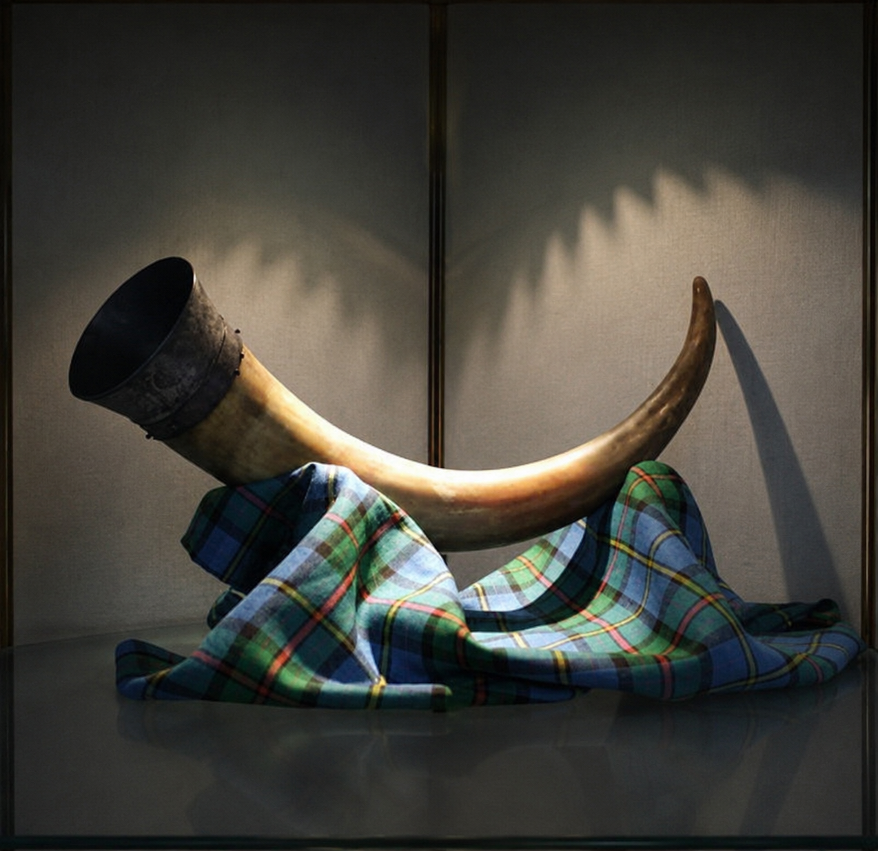 Drinking horn on tartan fabric display.