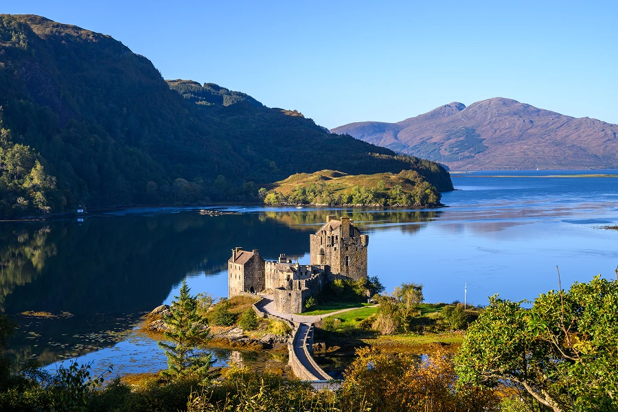 Castle by a serene lake and mountains.