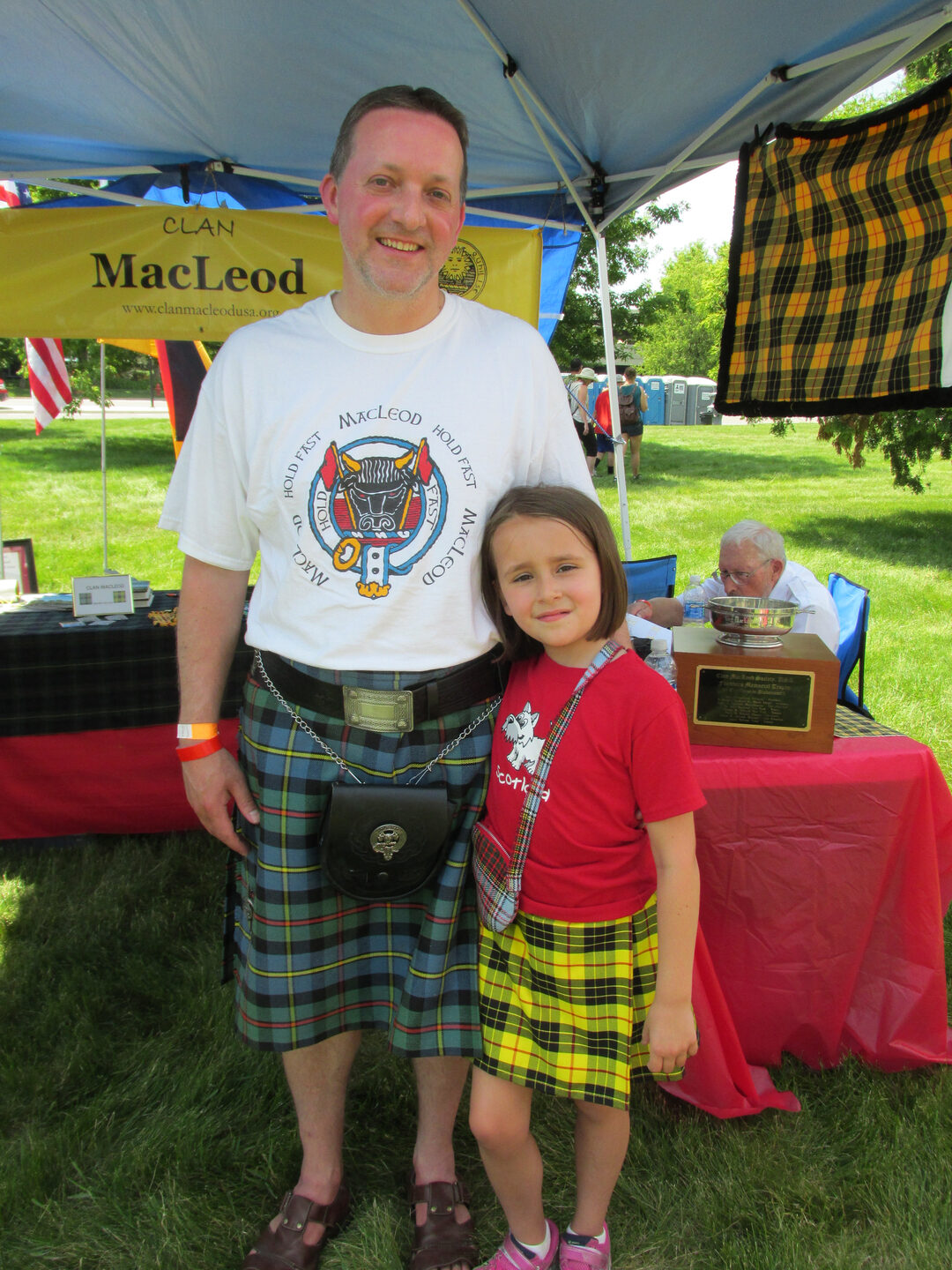 Man and girl at Scottish festival booth.