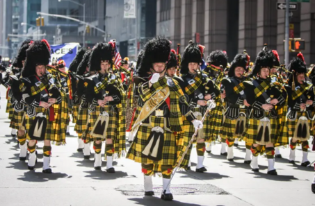 Marching band in traditional Scottish attire parade.