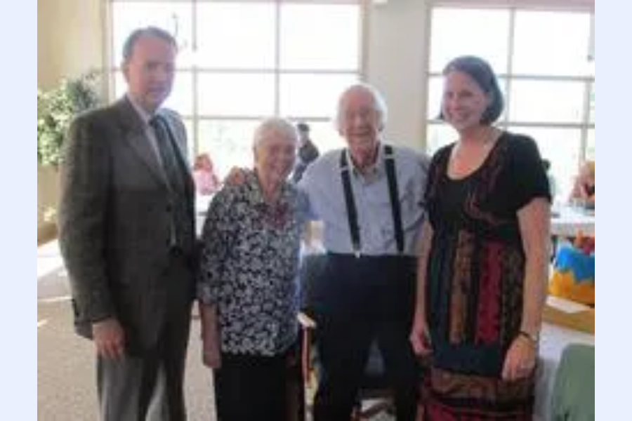 Four people smiling in a bright room.