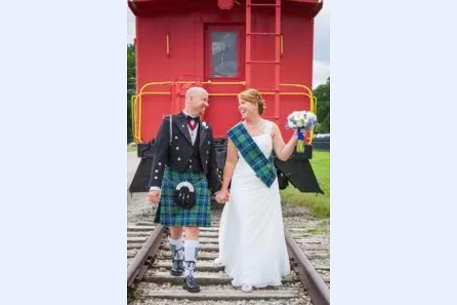 Bride and groom walking on train tracks.