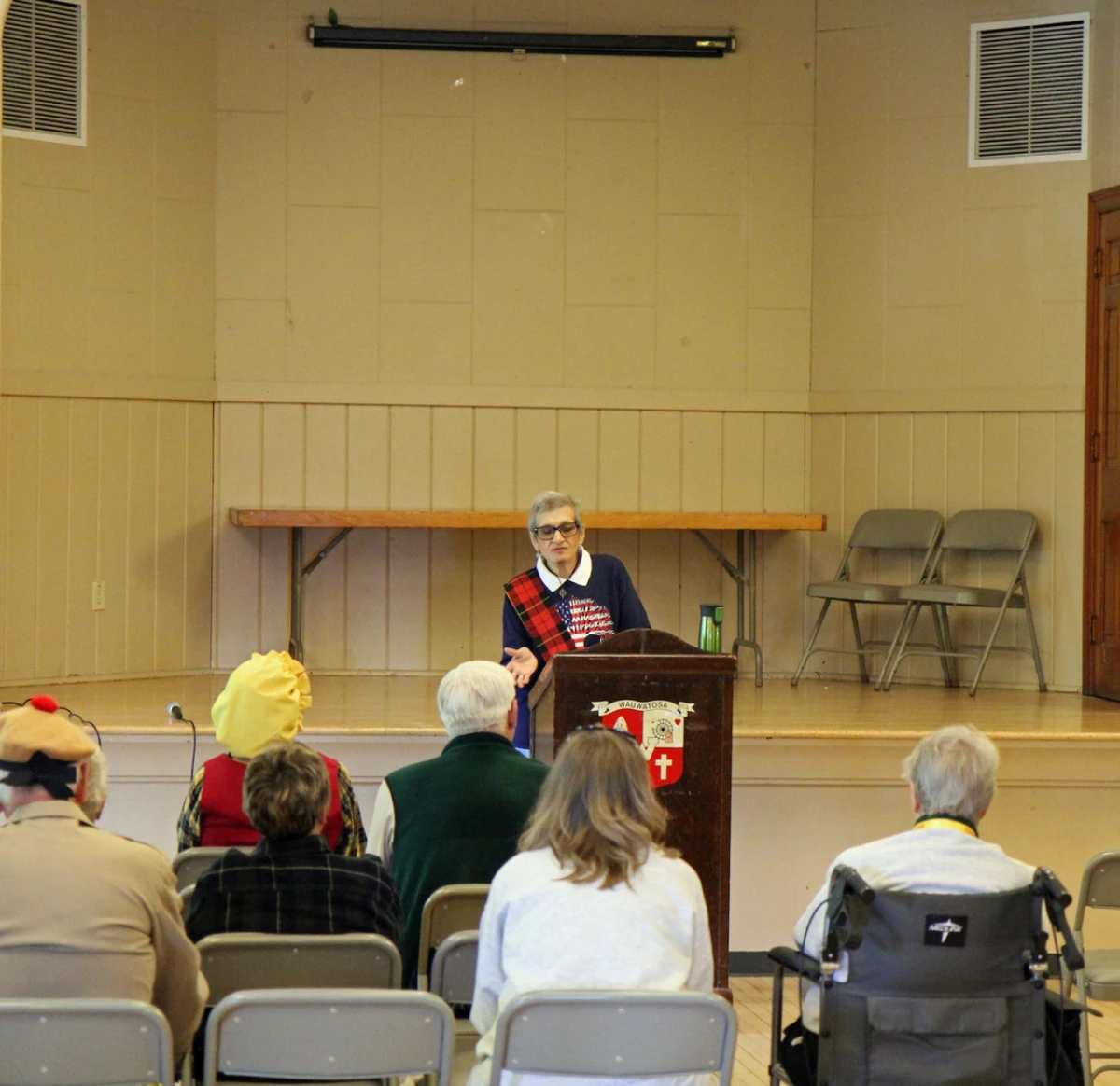 Speaker addressing audience in a community hall.