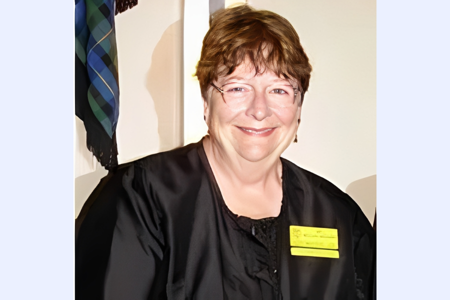 Smiling woman in black robe with badge.
